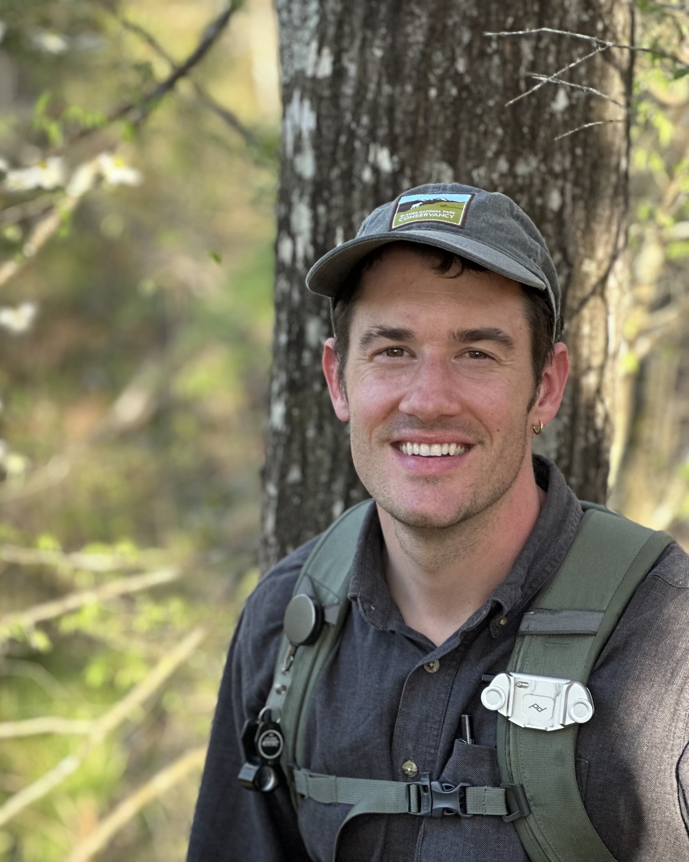 Headshot of a man in a hat and backpack